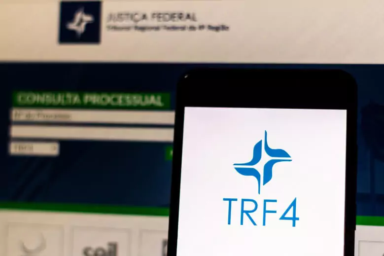 Celular com app do TRF4 e site ao fundo